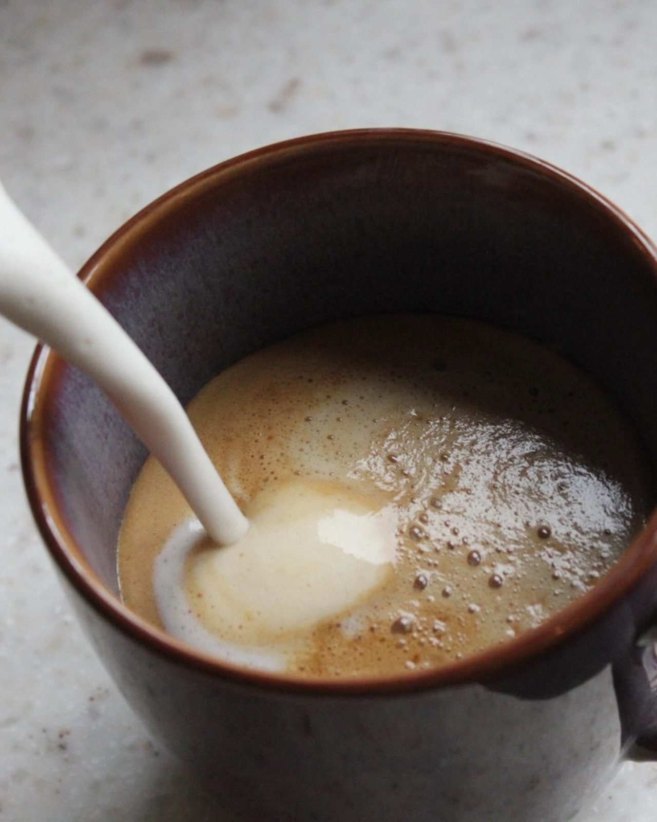 Milk poured into a fresh latte in a ceramic mug